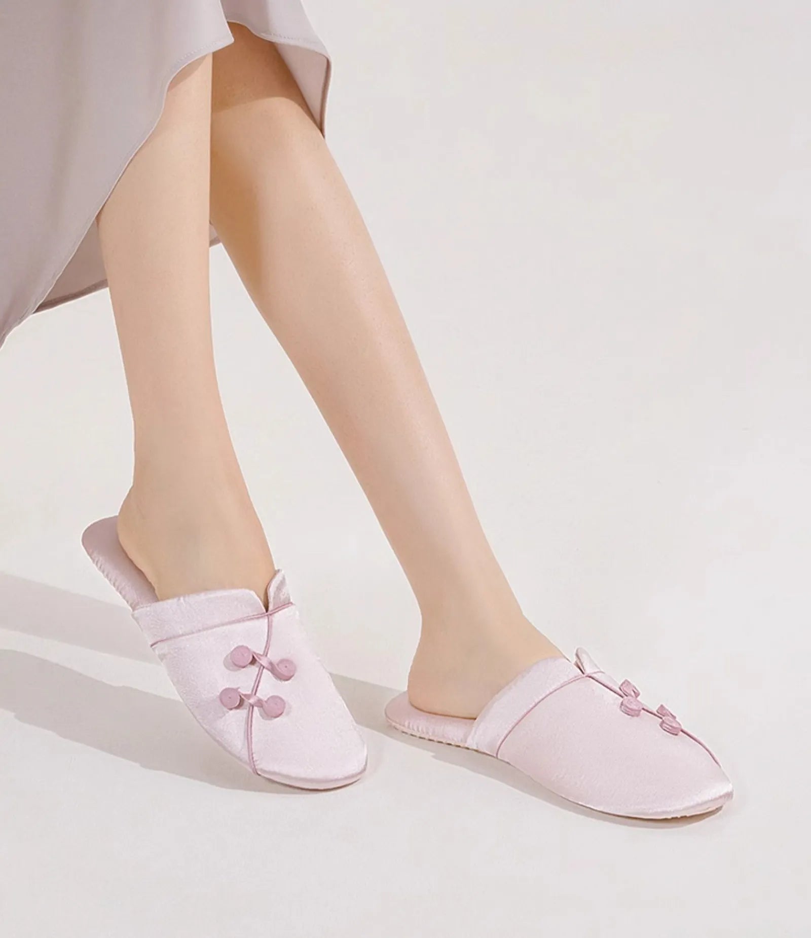 Model wearing Blush Pink Silky Floral Knot slippers with crossed legs - RoomDen