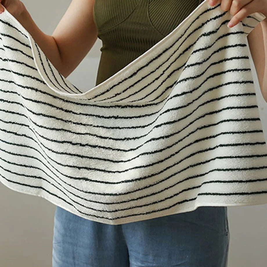 A woman stretching out a white and black striped face towel to show its texture and weave.
