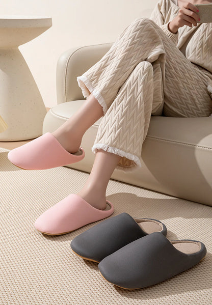Pink cotton house slippers on feet with grey pair on floor - RoomDen