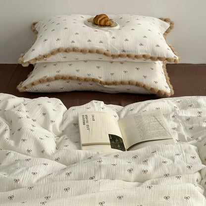 The bow print bedding set with pillows stacked and an open book, creating a study-in-bed vibe. - RoomDen