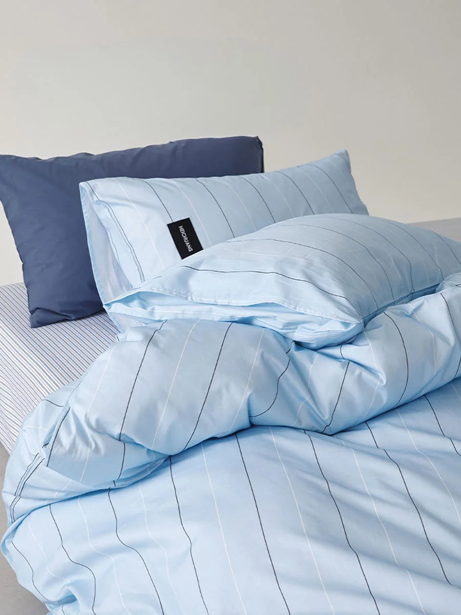 Angled close-up of the Sky Blue Pinstripe bedding, showing the contrast with the dark solid pillowcase - RoomDen.