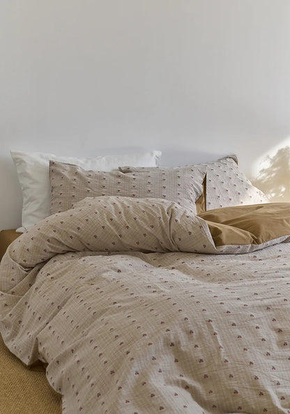 The Textured Ditsy Cherry Washed Cotton Bedding Set styled on a bed with soft morning light hitting the pillows - RoomDen.