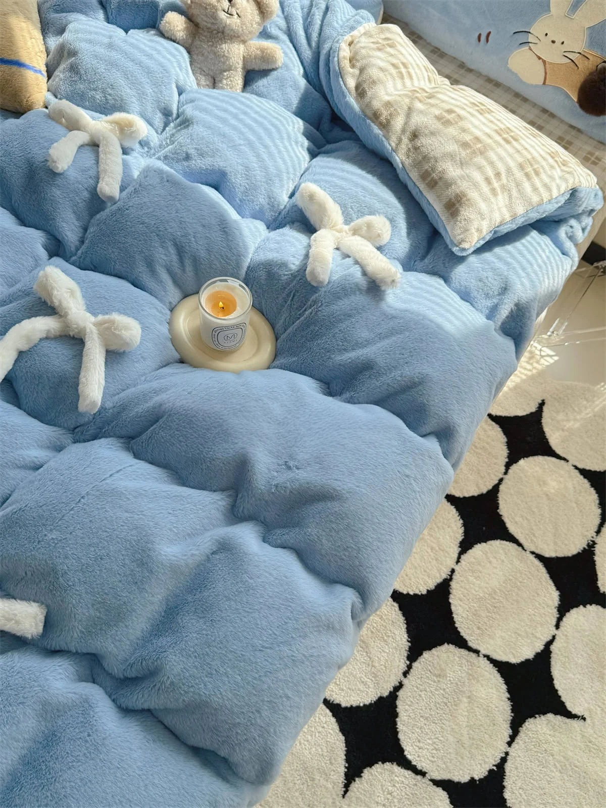 Angled top-down view of the blue tufted fleece comforter with a lit candle. - RoomDen