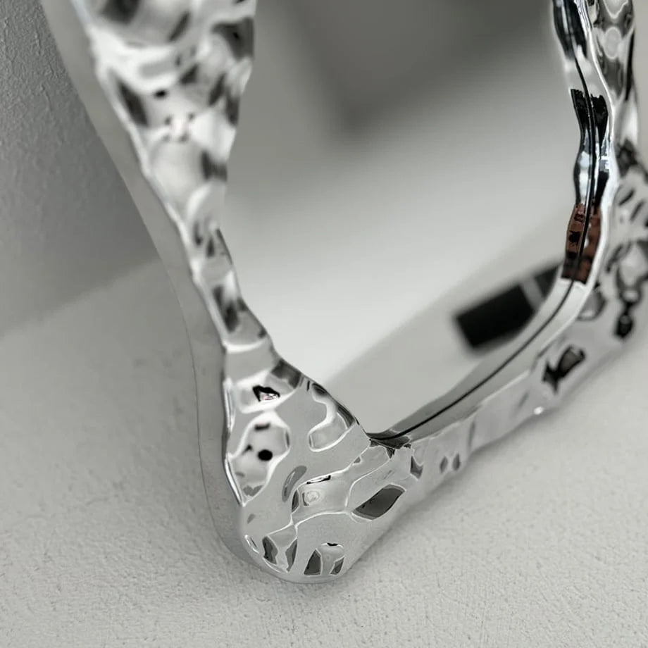 Macro shot focusing on the liquid-like texture and reflections on the mirror's chrome frame - RoomDen