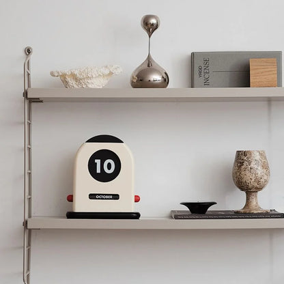 The perpetual calendar styled on a grey metal wall shelf with other Japandi decor pieces - RoomDen