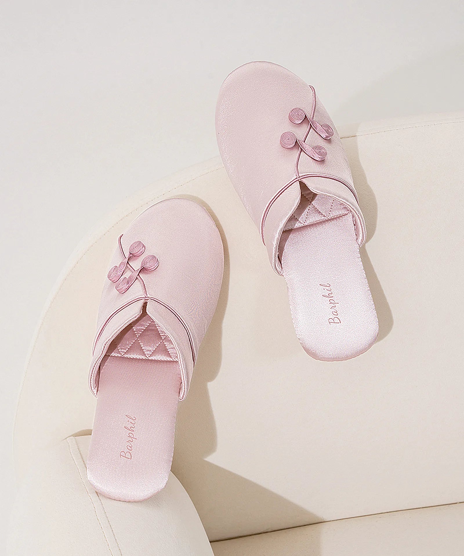Top view of Blush Pink house slippers on a cream armchair - RoomDen