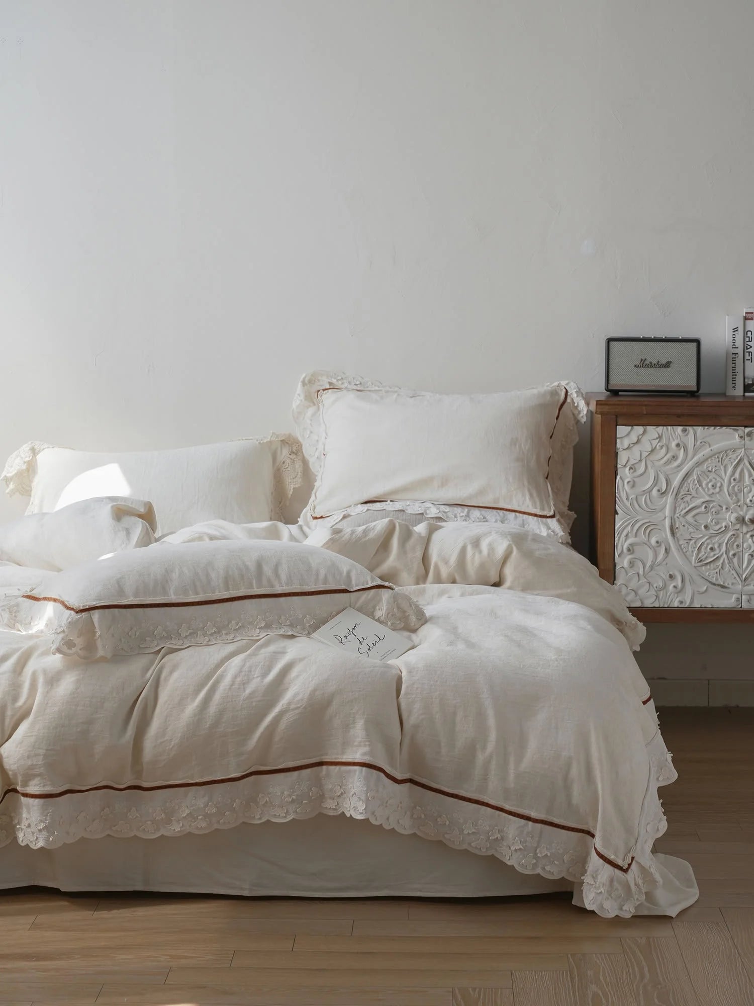 Full view of the Ruffle Lace Trim Linen Bedding Set, showing the duvet cover and pillows on a bed next to a carved white nightstand. - RoomDen
