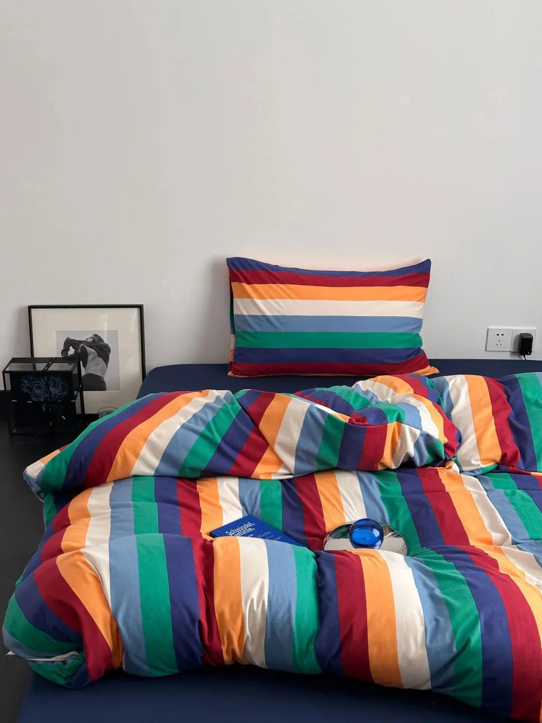 Top-down view of the colorful rainbow striped bedding set against a dark blue fitted sheet, highlighting the pattern - RoomDen