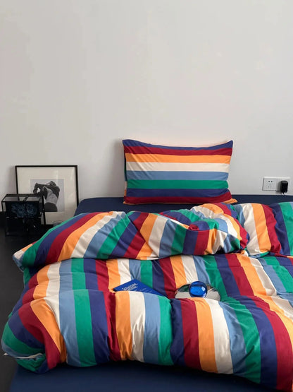 Top-down view of the colorful rainbow striped bedding set against a dark blue fitted sheet, highlighting the pattern - RoomDen
