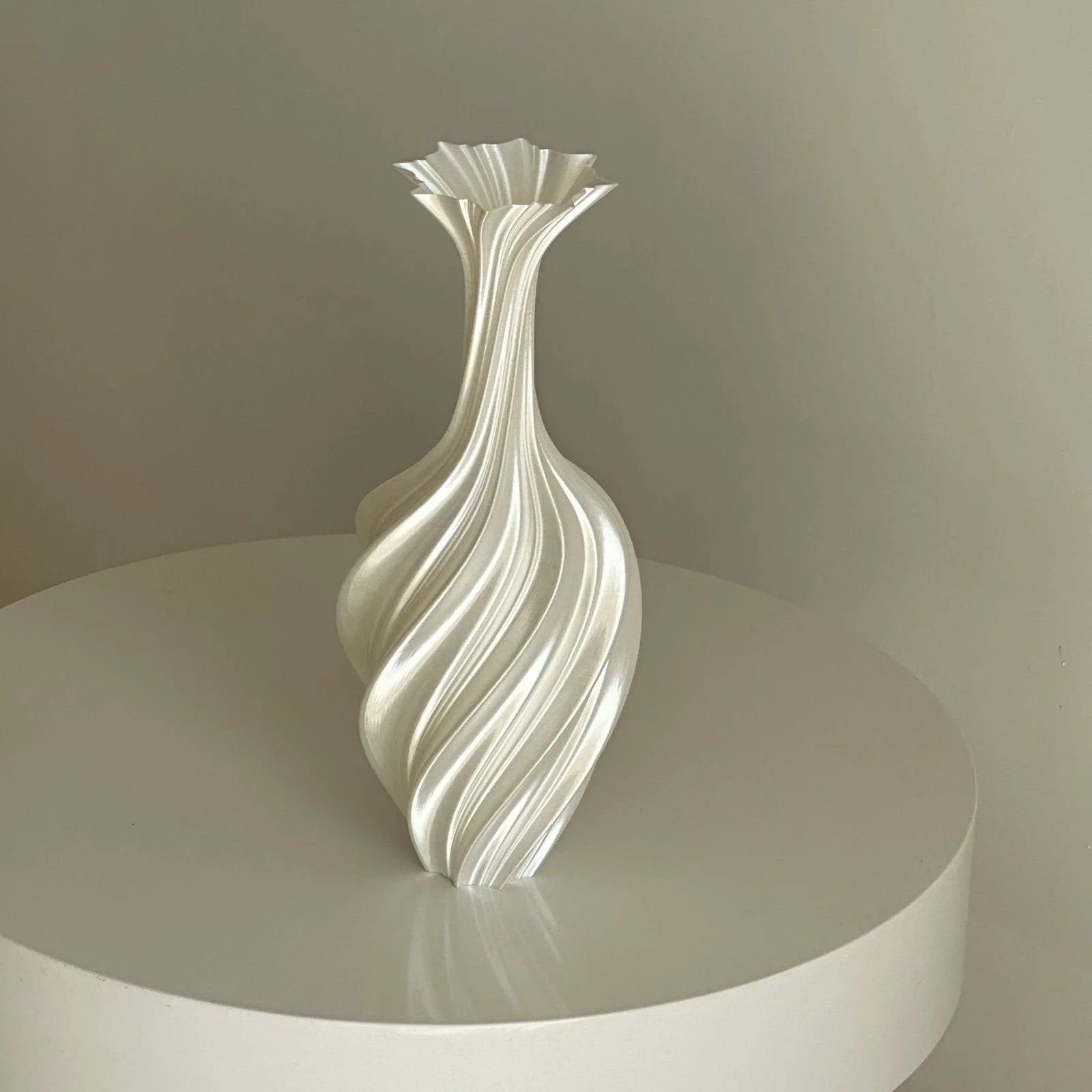 Pearl White Sculptural Swirl Ribbed PLA Vase on a white pedestal, full view - RoomDen