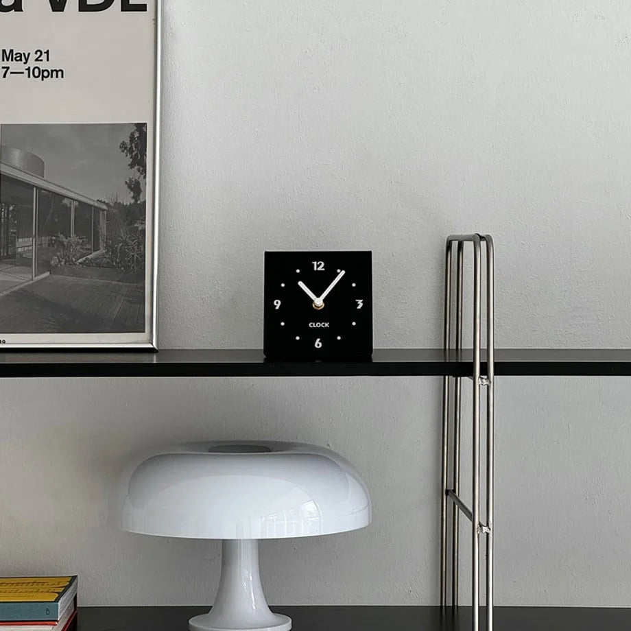 Front view of the black minimalist clock on a shelf, showing its clean design. - RoomDen