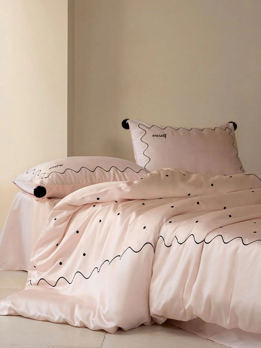 Side view of a bed with the Pastel Pink & Black silky Tencel bedding set, showing the pom pom pillowcase. - RoomDen