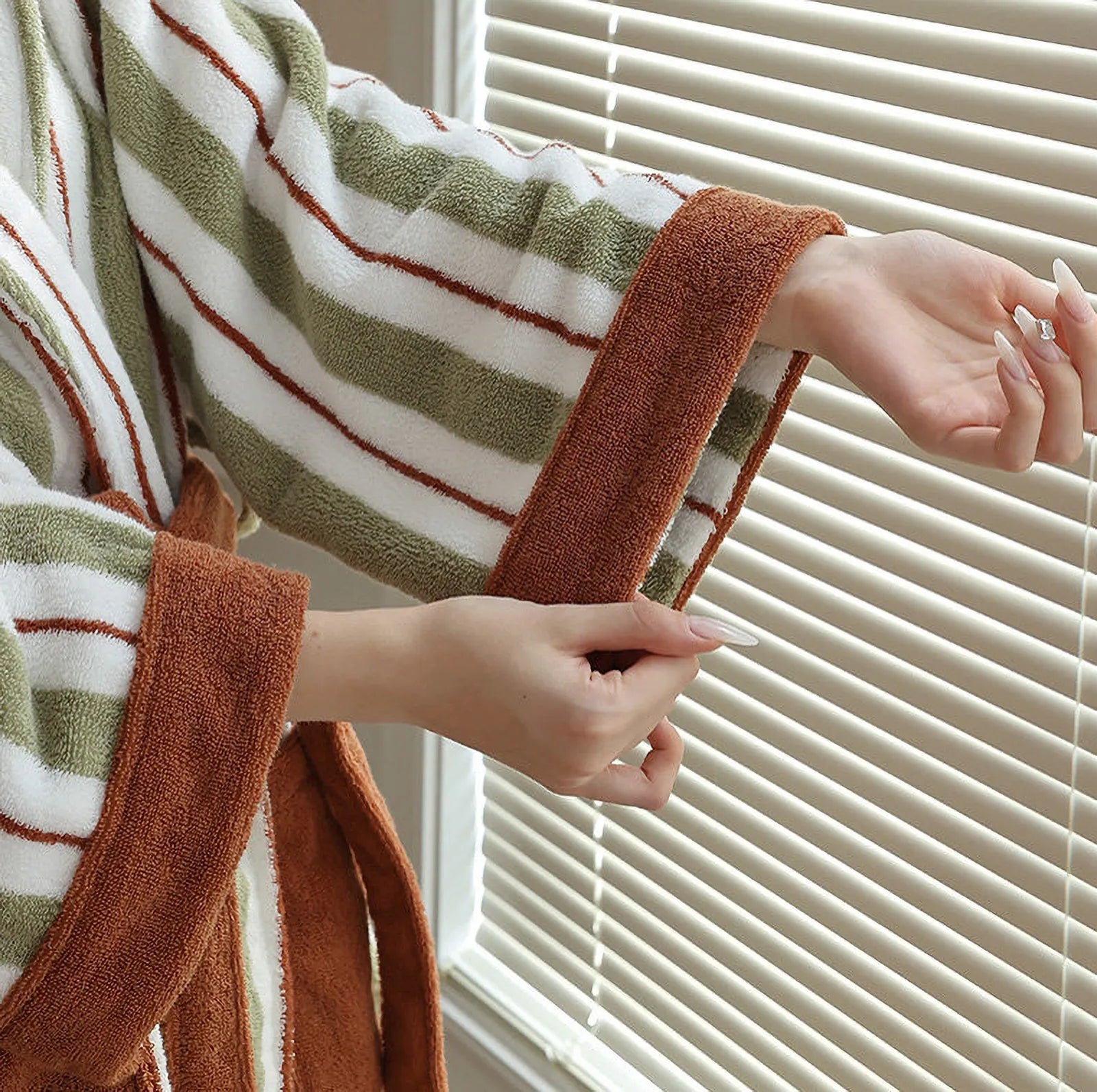 Close-up of the rust-colored cuff detail and green striped texture of the RoomDen robe.