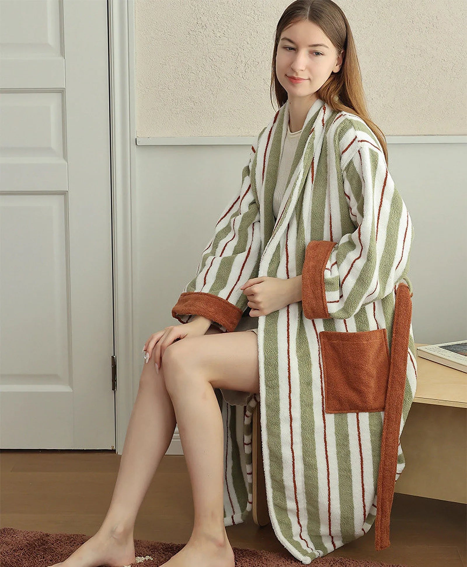 RoomDen Plush Sage Striped Long-Staple Cotton Robe shown on model sitting on a bench.