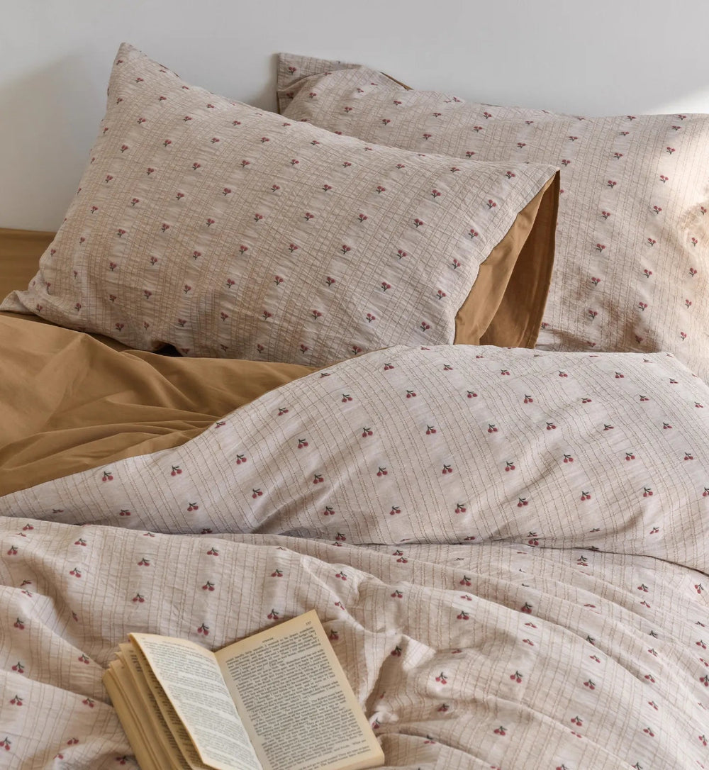 Close-up of the Textured Ditsy Cherry Washed Cotton Bedding Set with an open book resting on it - RoomDen.