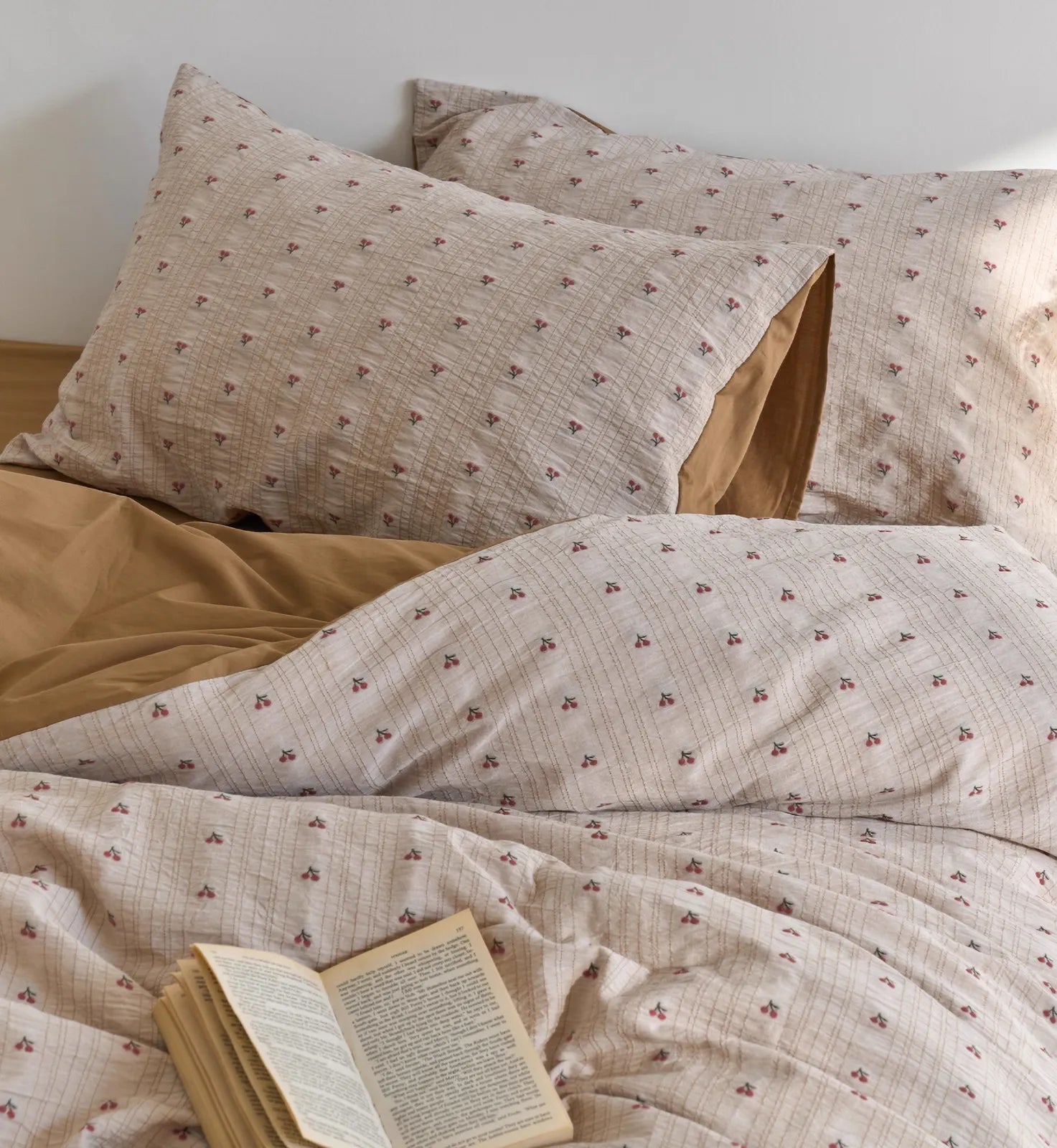 Close-up of the Textured Ditsy Cherry Washed Cotton Bedding Set with an open book resting on it - RoomDen.