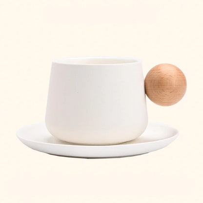 A studio shot of the Creamy White Frosted Ceramic Mug and Saucer Set with a wooden ball handle, showing a different angle. - RoomDen
