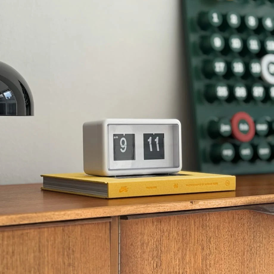 Minimalist retro flip clock in white on a wooden desk with a yellow book. - RoomDen