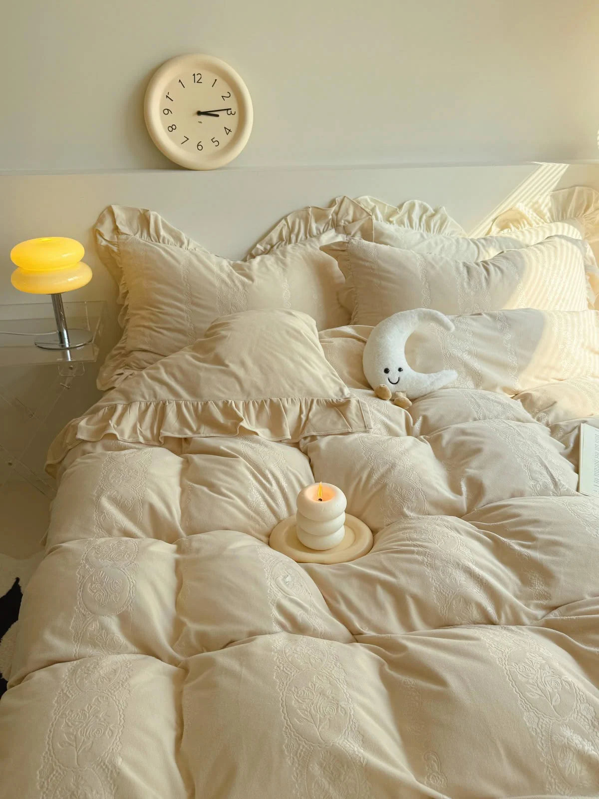Cozy bedroom scene featuring the Creamy Beige Ruffled Velvet Bedding with a candle and moon plushie. - RoomDen