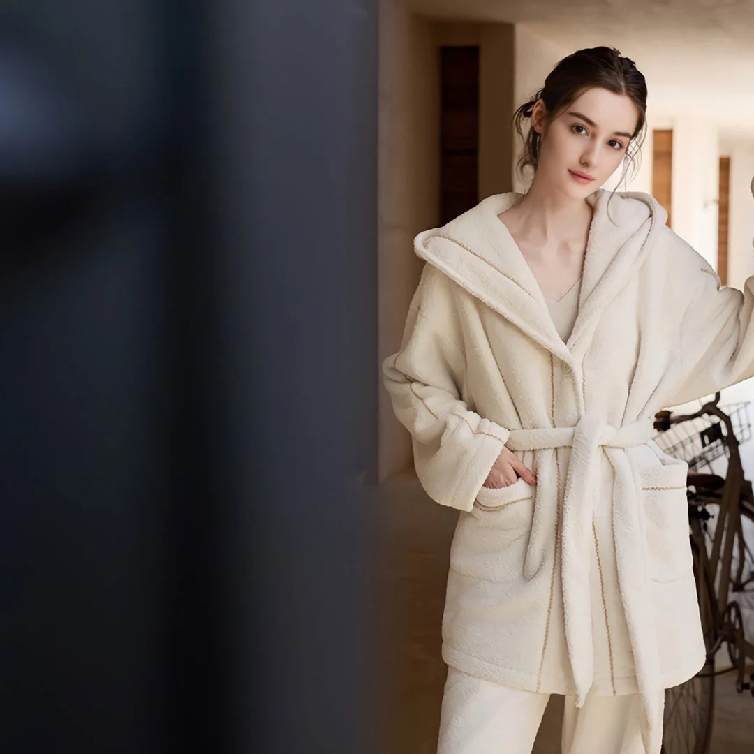 Model with hand in pocket of a creamy white hooded fleece robe and pajama set - RoomDen.