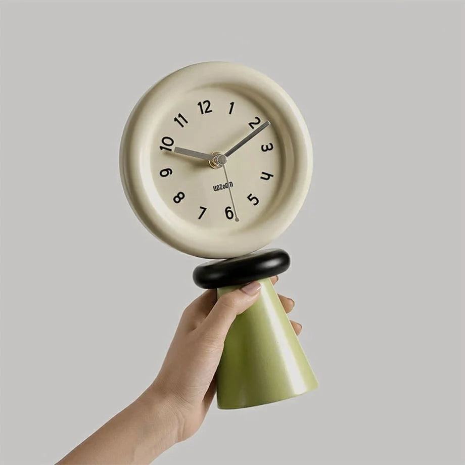 Hand holding the green and beige sculptural wood table clock to show its size and matte finish. - RoomDen