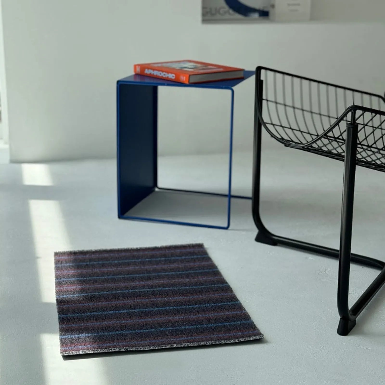Perspective view of Dark Grey Striped PVC Coil Rug in a modern minimalist room
