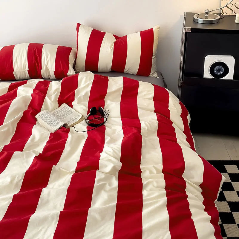 Overhead view of the Red & Cream Bold Stripe Cotton Bedding Set with an open book and headphones - RoomDen