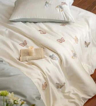 Detailed overhead shot of the butterfly embroidery on the silky Tencel duvet cover.