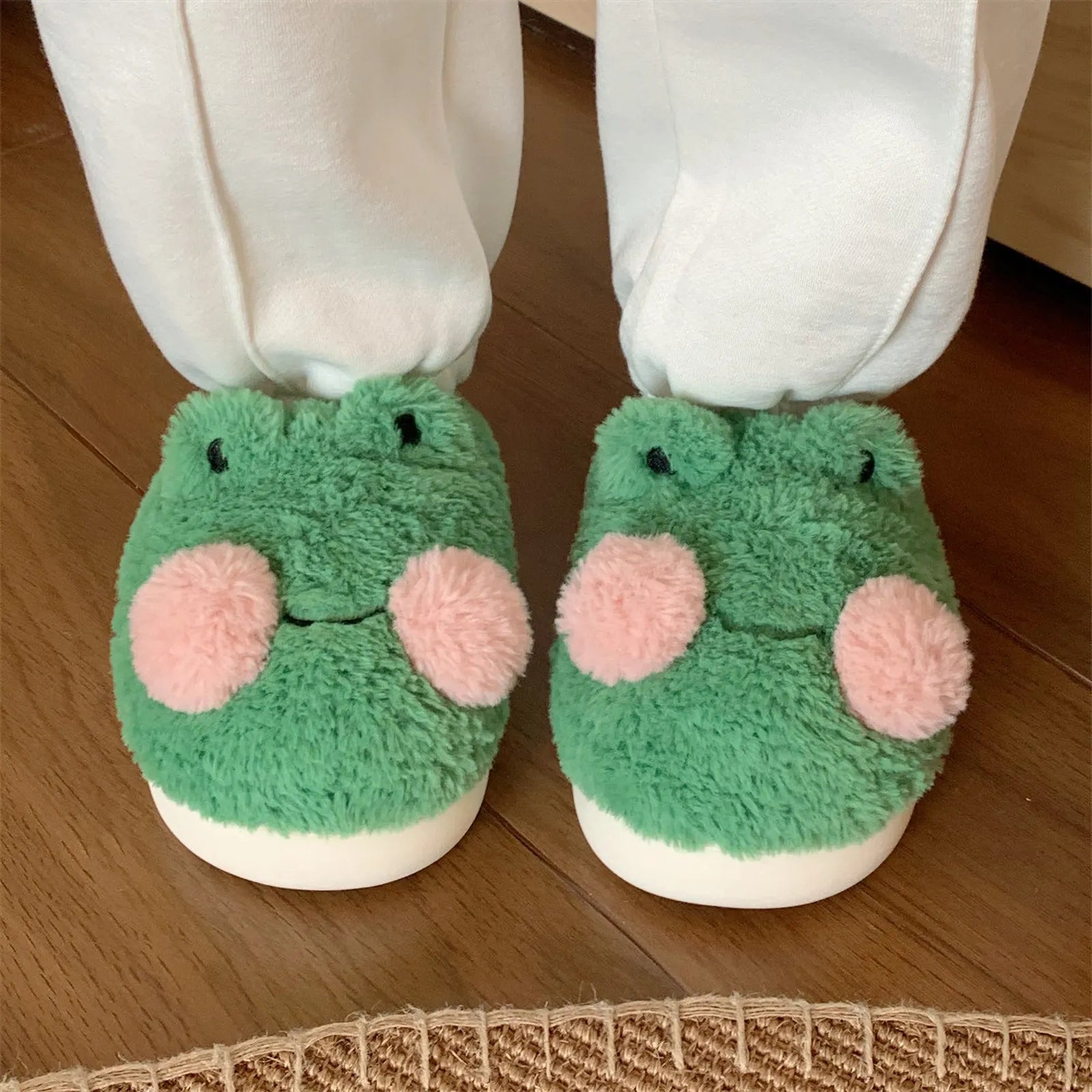 Front view of green 3D frog plush house slippers on feet - RoomDen