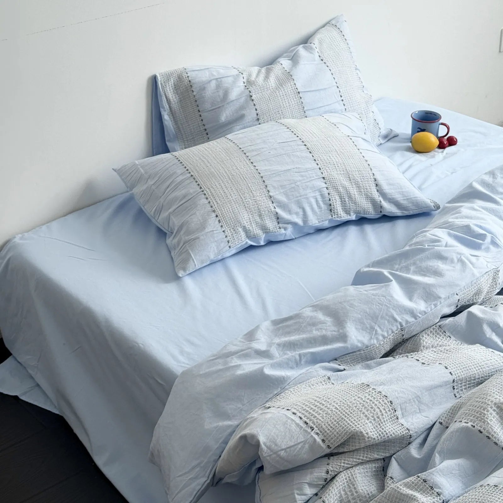 Full view of the Sky Blue textured woven stripe bedding set on a bed with a dark floor.