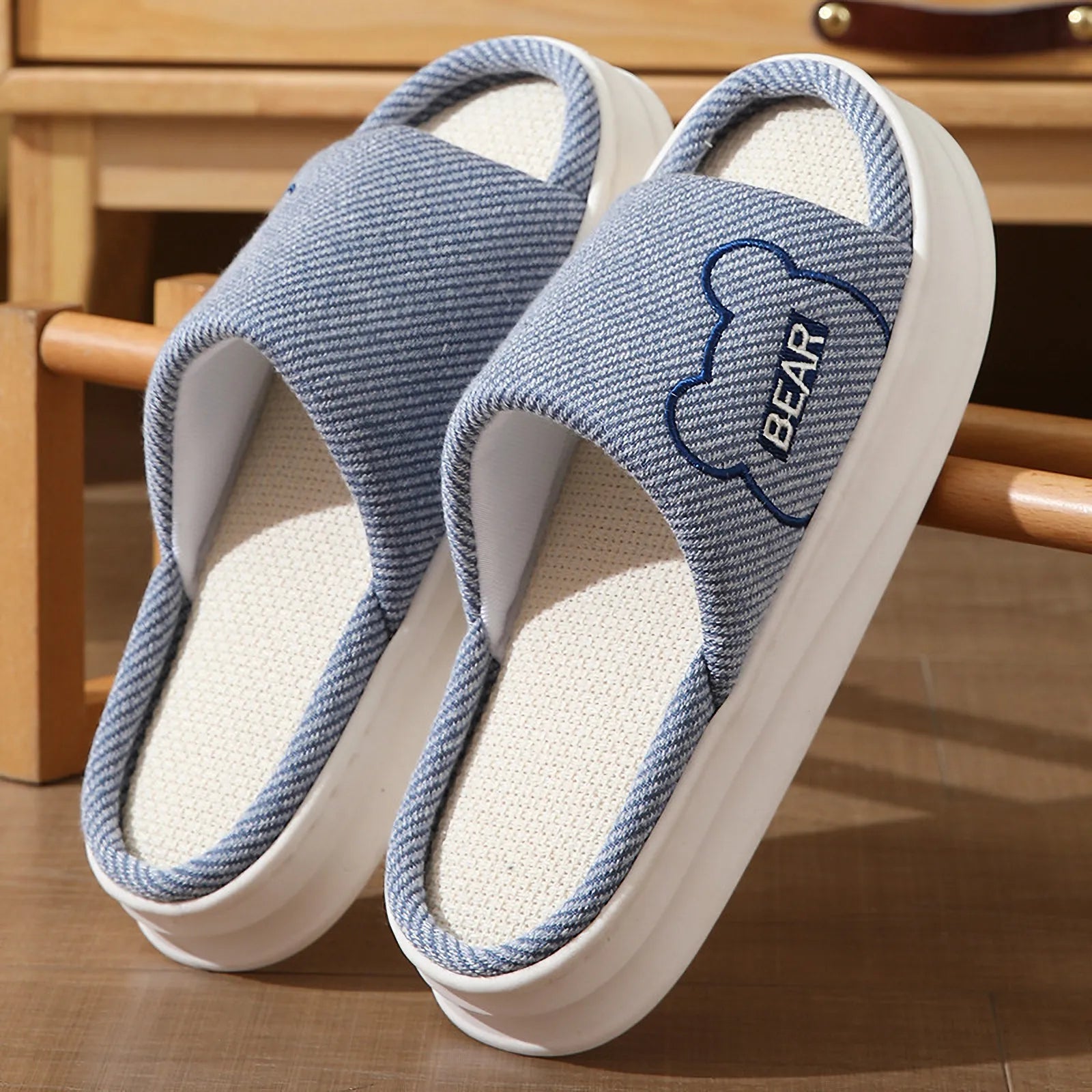 Close up of Blue woven linen slippers showing embroidered bear detail and open toe design