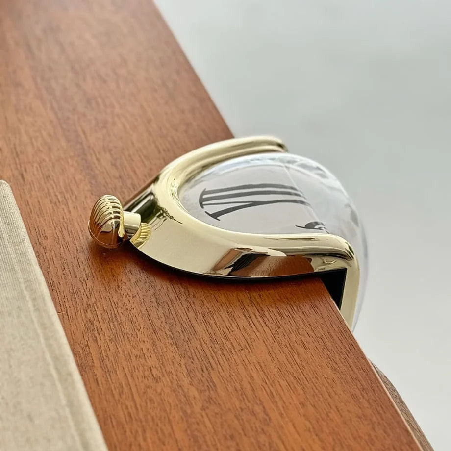 Detail of the gold melting clock's winder and curved edge on the dresser.