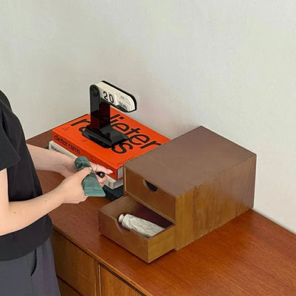 A person placing a tube of cream into the open drawer of the wooden desktop organizer. - RoomDen