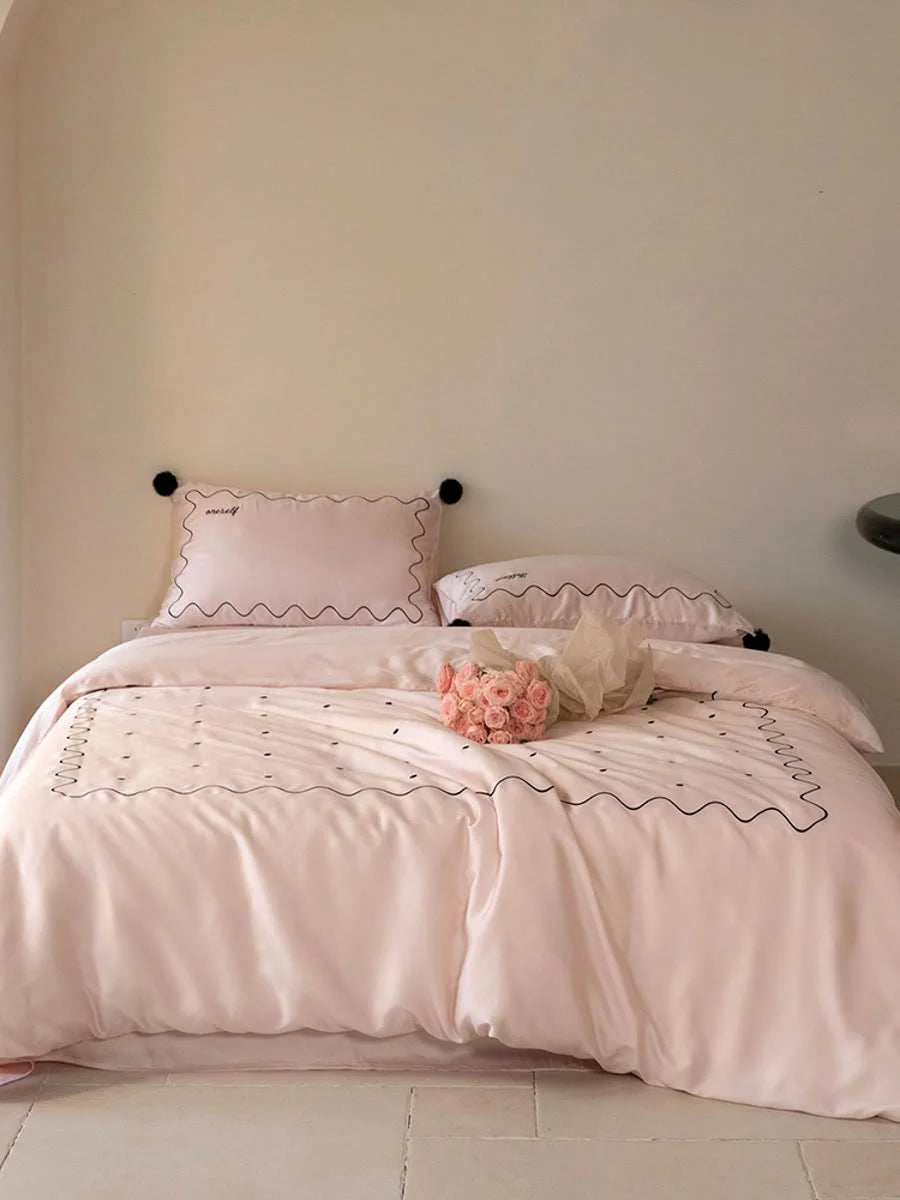 Full view of a bed made with the Pastel Pink & Black pom pom Tencel bedding set in a neutral-walled room. - RoomDen