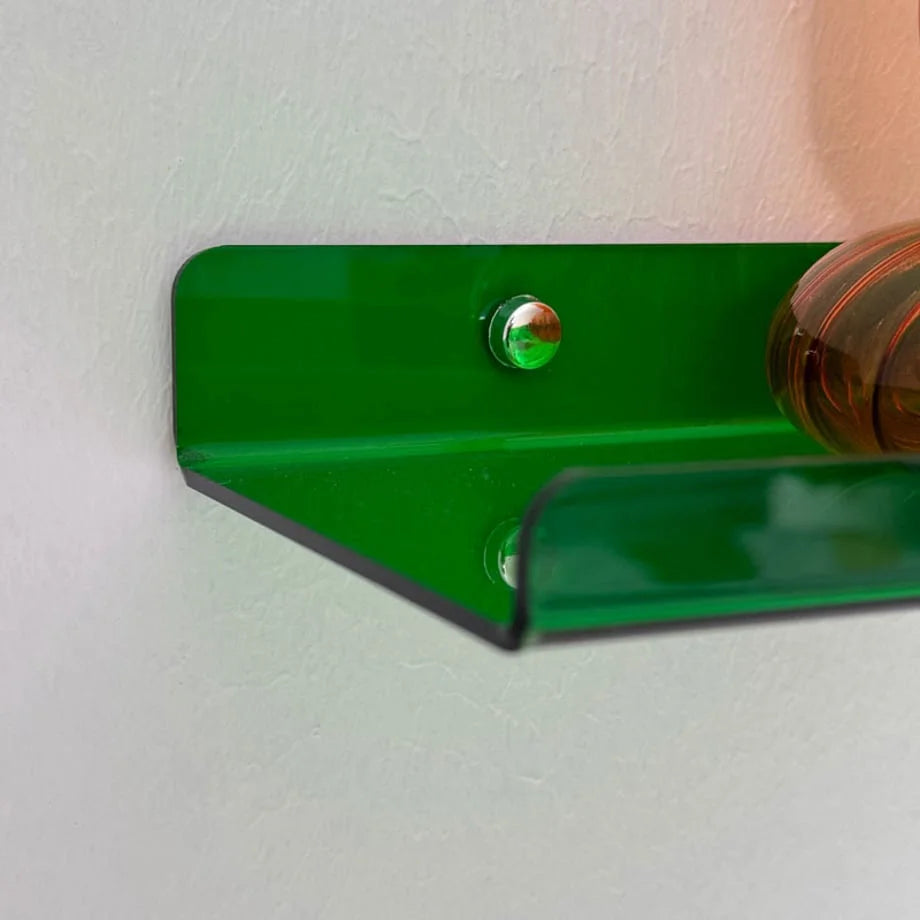 Detail shot focusing on the silver mounting hardware of the green acrylic wall shelf.