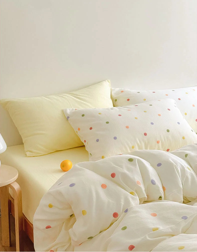 The Polka Dot duvet cover partially folded back to show the yellow fitted sheet, with a small orange accent - RoomDen