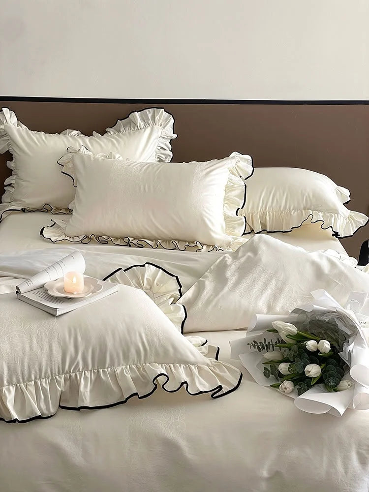 Close-up on the ruffled pillows and duvet cover of the Cream White bedding set, with a bouquet of tulips - RoomDen.