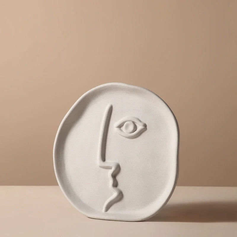 Close-up of the round, plate-like abstract face vase with a profile design - RoomDen.