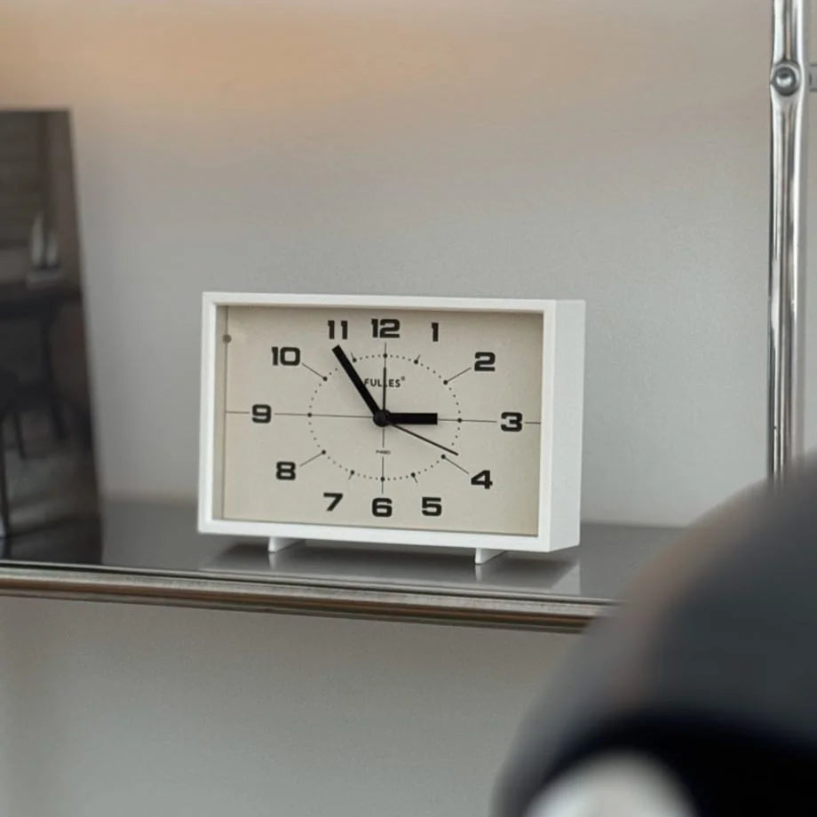 Close-up of the Cream White Retro Table Clock on a metal shelf.