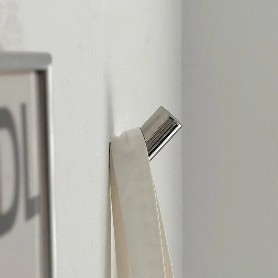 Side profile of the polished metal decorative hook, showing its angled design and how it holds items. - RoomDen