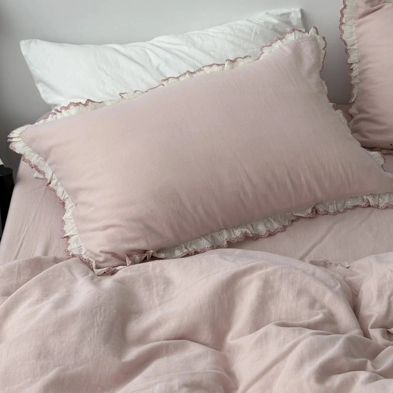 Close-up view focusing on the dusty rose pillowcase with its charming embroidered lace ruffle trim.