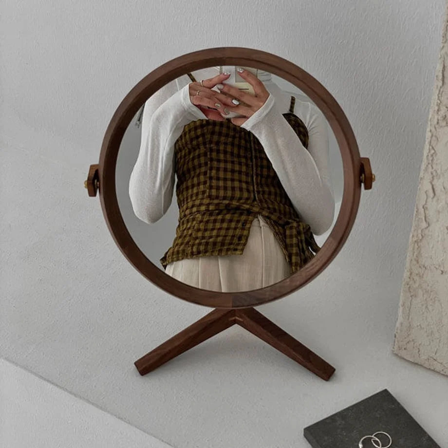 Reflection of a person in the round walnut table mirror, showcasing its clear surface and size.