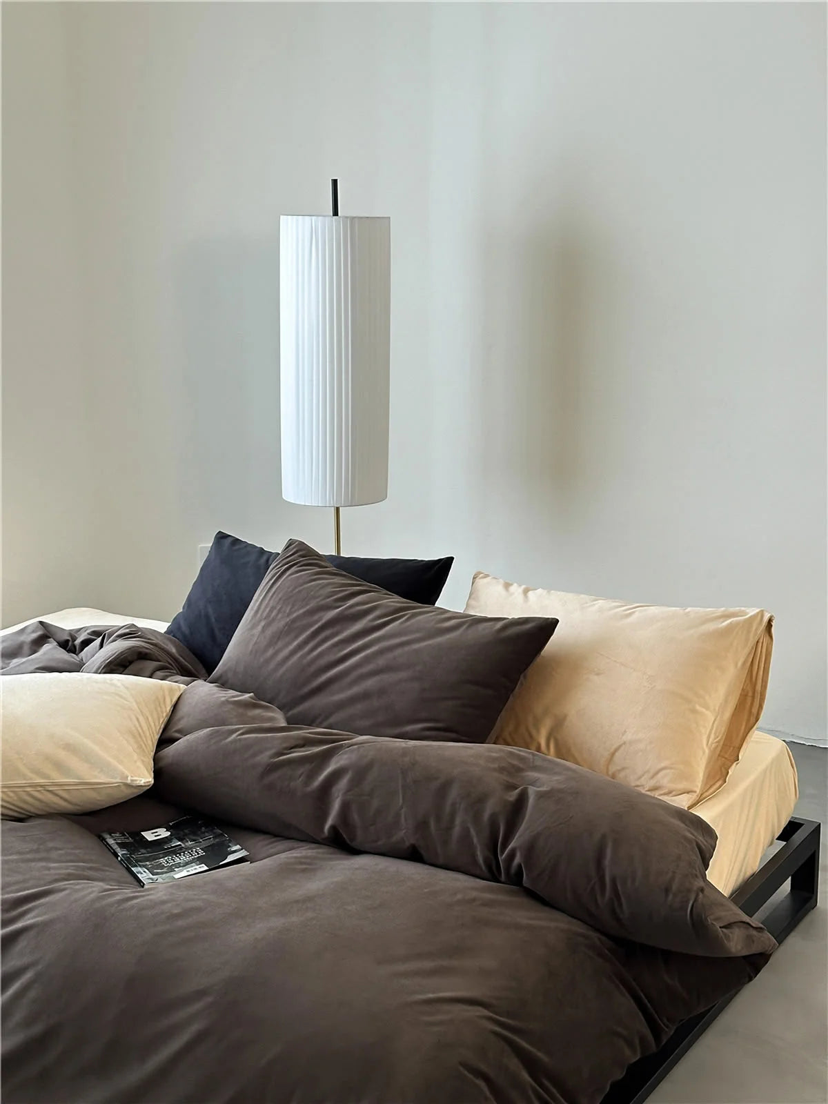 A mix of Mocha Brown, cream, and black velvet pillows on a bed, showcasing styling versatility. - RoomDen
