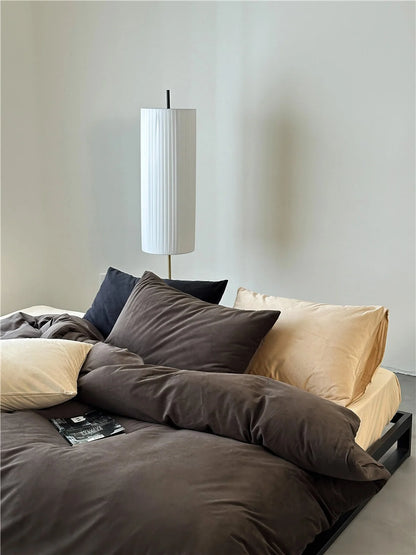 A mix of Mocha Brown, cream, and black velvet pillows on a bed, showcasing styling versatility. - RoomDen
