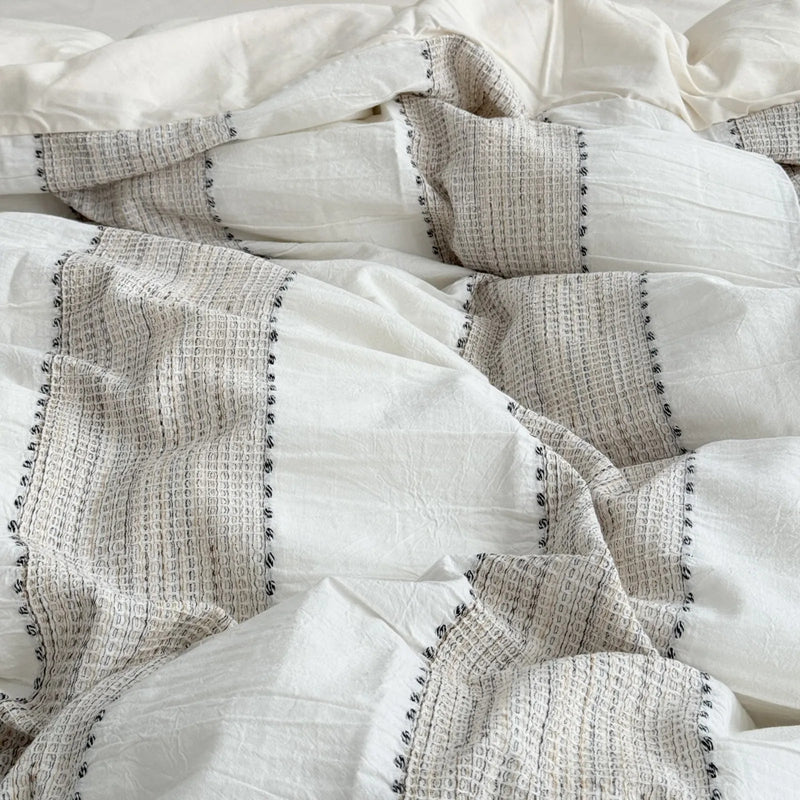 Detailed texture of the woven stripes and soft wrinkles on the oatmeal beige duvet cover. - RoomDen