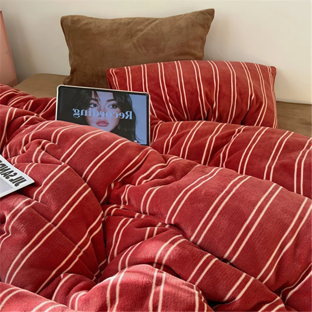 Close-up lifestyle shot of the Plush Pinstripe Velvet Bedding Set in red, with a tablet showing a face on the bed - RoomDen
