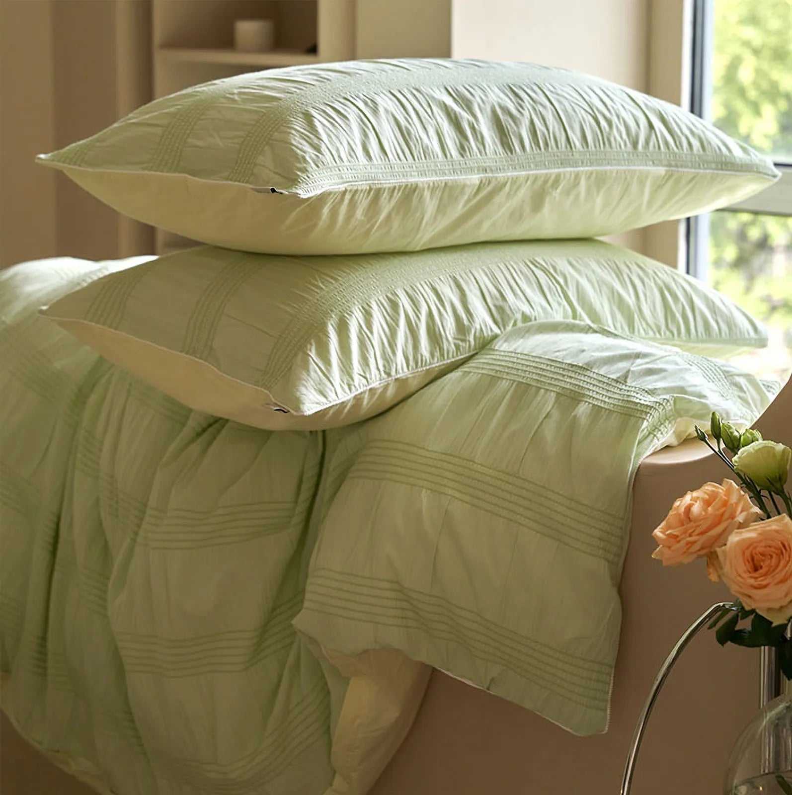 Pistachio Green pintuck duvet cover and pillows draped over a bed frame, showing the fabric's soft drape.