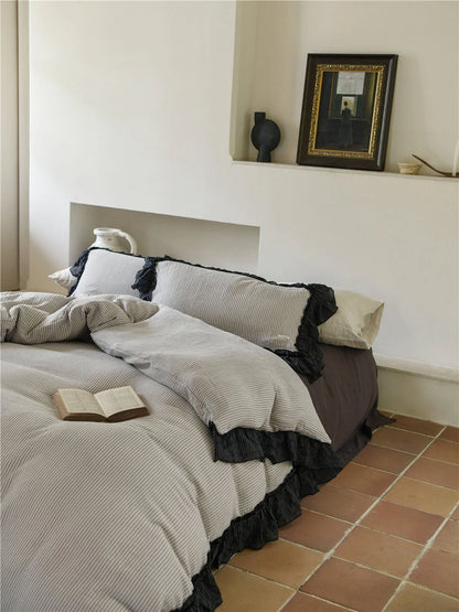 Lifestyle shot of the pinstripe ruffle bedding set with a book, highlighting the cozy bedroom aesthetic. - RoomDen