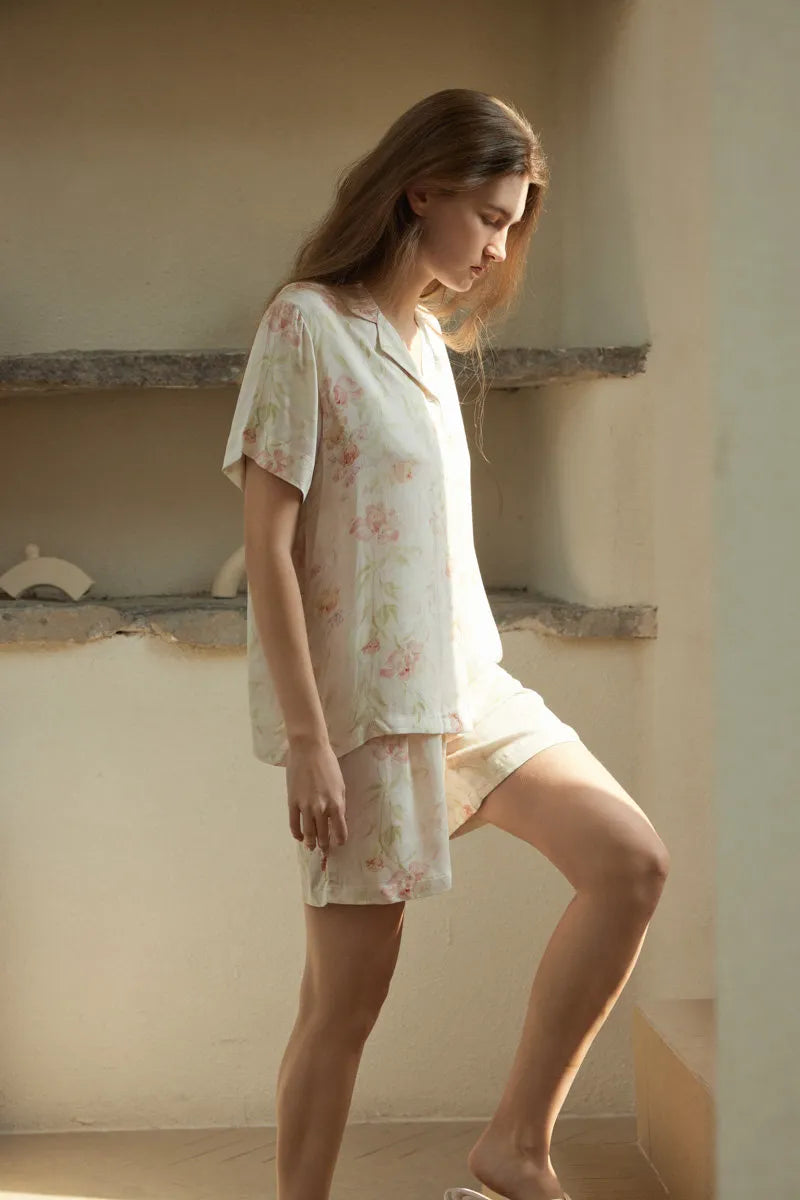 RoomDen Beige Floral Pajama Set - Full body side view walking up stairs in sunlight