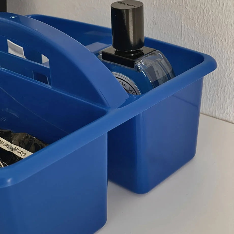 Close-up on the handle and interior of the blue storage caddy holding a perfume bottle. - RoomDen
